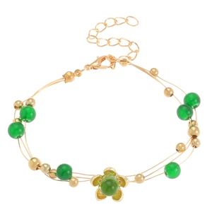 Detalle de pulsera triple de oro con diseño de flor, cuentas verdes y cierre de mosquetón