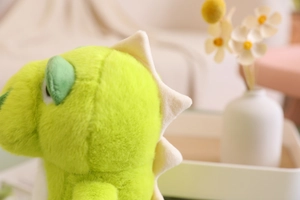 Close-up of soft green plush dinosaur fabric with cream-colored back spikes detail