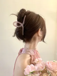 Detail of a large matte dusty pink claw clip worn by a model in a twist hairstyle