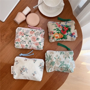 Detailed top view of four floral cotton mini pouches with zipper pulls on a wooden desk