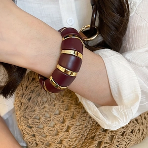 Detailed shot of dark red acrylic segments and golden rings on an elastic bracelet
