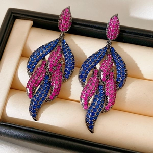 Detailed macro shot of vintage leaf-shaped earrings with pink and blue zircons in black gold