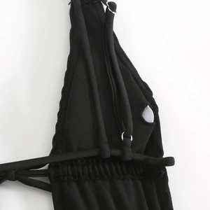 Dettaglio di costume nero con spalline regolabili e connettori ad anello in metallo argento