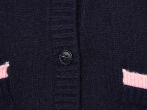 Detailed macro view of dark blue knit cardigan with pink ribbing and black button closure