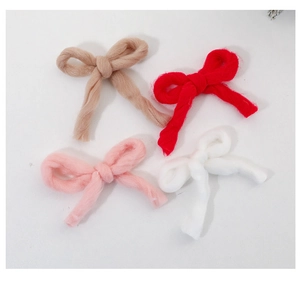 Detailed overhead view of four knit wool bow Christmas tree ornaments in assorted colors
