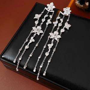 Macro detail of silver tassel earrings with zircon petals on black leather case