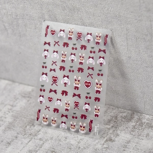 Detailed macro shot of embossed nail art stickers with cute rabbits and red bows