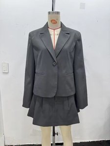 Détail de l'ensemble blazer gris foncé et jupe plissée sur un mannequin de couture