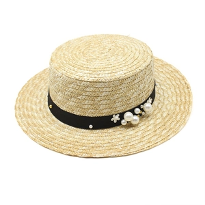 Handwoven straw boater hat featuring elegant pearl and floral accents on a black ribbon