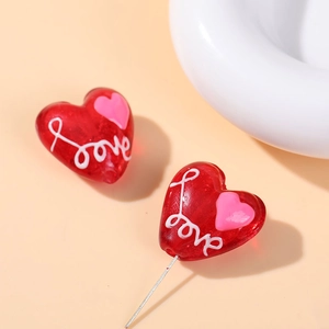 Macro detail of red heart glass beads with love script for DIY jewelry making