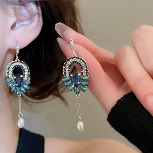 Détail de boucles d'oreilles bohèmes avec cristal bleu, pierres vertes et perles