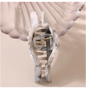 Detail view of marble pattern hair claw clip with golden metal spring mechanism