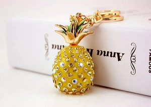 Macro view of crystal pineapple keychain with yellow rhinestones next to a white book