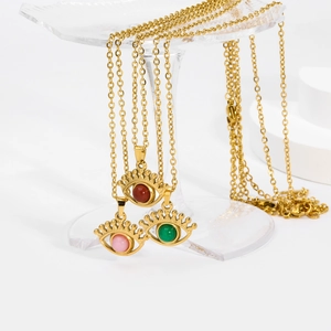 Detailed shot of evil eye pendant necklaces in red, green, and pink stones on gold chains