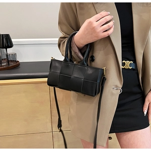 Borsa a mano in pelle intrecciata nera con tracolla indossata da una modella in tailleur