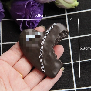 Macro shot of a chocolate heart magnet with bite mark and text for home decoration