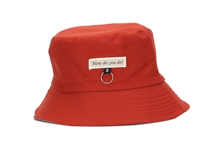 Detail of red bucket hat with How do you do? patch and silver ring on white background