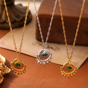 Gold and silver evil eye pendant necklaces with green zircon on a vintage desk