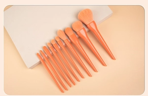 Detail view of 10 orange makeup brushes with dense bristles on a geometric display