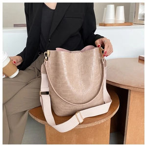 Detail of khaki bucket bag with crocodile embossing and wide woven adjustable strap