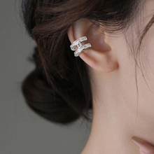 Detail of silver ear cuff with cubic zirconia micro-pave setting on model's ear
