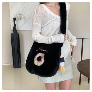 Detail of plush black shoulder bag with donut embroidery and cute duck charm accessory
