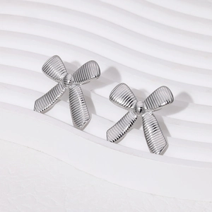 Macro view of silver bow-shaped stainless steel earrings with textured metallic finish
