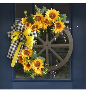 Close-up of rustic sunflower wreath with wooden wheel and checkered bow on blue door