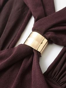 Close-up of golden metal ring hardware on deep purple knit fabric texture detail