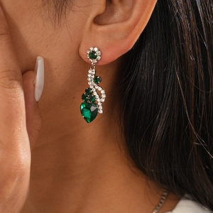 Gros plan de boucles d'oreilles cœur en cristal vert avec pompons en strass brillants