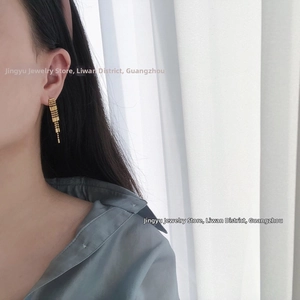 Macro detail of gold-plated fringe tassel earrings with bead curtains on a model