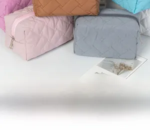 Detail of quilted cosmetic bags with metal zippers in multiple colors stacked on white