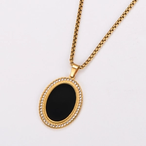 Close-up of 18k gold plated oval pendant with black enamel center and crystal border
