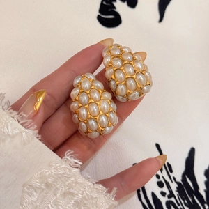 Detail of vintage gold-plated teardrop earrings featuring densely set white pearls