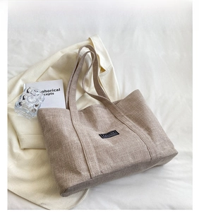 Khaki woven tote bag detail showing linen texture and logo patch on soft fabric