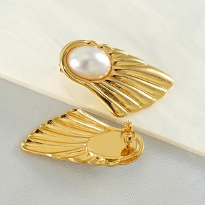 Macro shot of fan-shaped vintage earrings with gold texture and white pearl center