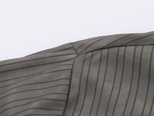 Close-up of shoulder seam on grey-green striped shirt showing fine stitching and woven fabric