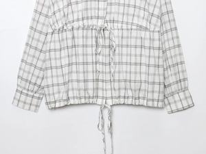 Détail de la veste à carreaux noir et blanc montrant la taille et l'ourlet à cordon