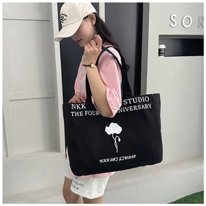 Lifestyle shot of large canvas tote bag with floral print and NKK letters on shoulder