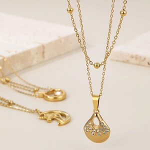 Macro detail of 18K gold-plated double-layer necklace with sparkling drop pendant and beads