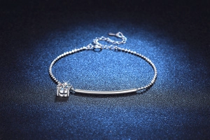 Macro shot of silver beaded bracelet with polished curved bar and Moissanite charm