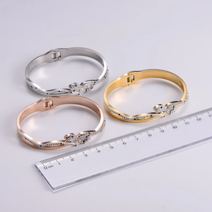Macro shot of three snake-shaped titanium steel bracelets in silver, gold, and rose gold finishes