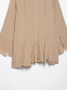 Close-up of khaki chiffon dress hem featuring pleated details and asymmetrical side slit