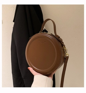 Detail der runden braunen Ledertasche mit Rundgriff und eingraviertem Text vorne