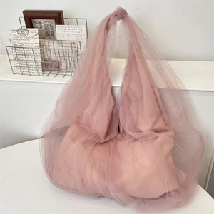 Detail of pink mesh tote bag with romantic knotted handle and soft layered fabric design