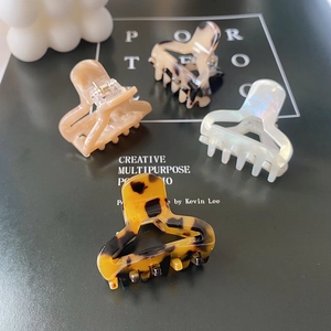 Close-up of four assorted acetate hair claws in leopard and marble patterns on a magazine