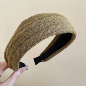 Détail d'un serre-tête en tricot marron montrant la texture épaisse à côtes verticales