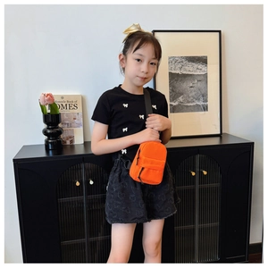 Girl wearing orange mini nylon crossbody chest bag with adjustable black shoulder strap