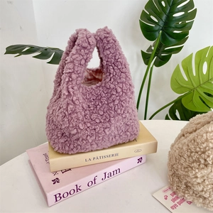 Detail of purple faux shearling handbag with soft texture and plaid lining on books