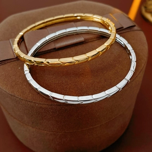 Detailed close-up of gold and silver plated arrow pattern bangles on a brown suede jewelry box